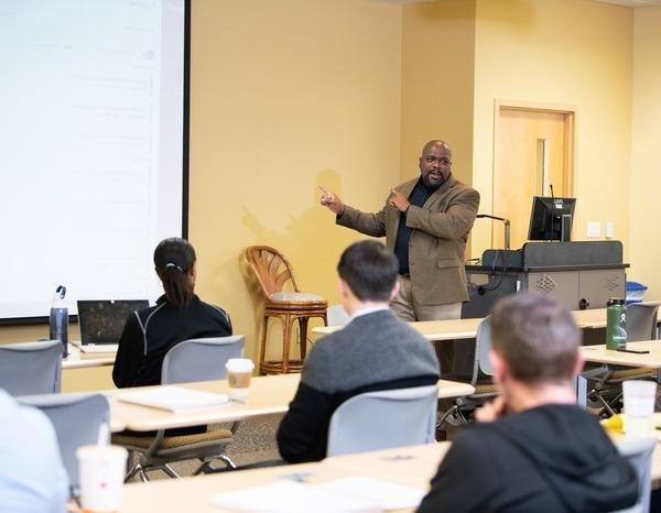 A male professor teaching students in a Davis College of Business & Technology classroom.